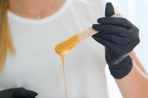 Portrait of a female caucasian beautician holding a jar of sugar paste for sugaring photo