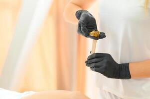retrato de un hembra caucásico cosmetólogo participación un tarro de azúcar pegar para azucarado foto