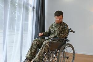 Handsome soldier sitting in a wheelchair on gray background photo