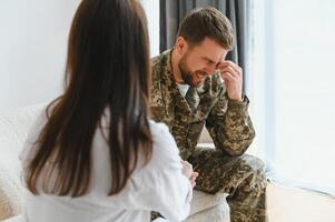 Sad male soldier on appointment with psychologist at office photo