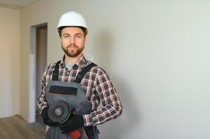 retrato de positivo, hermoso joven masculino constructor mientras trabajando a construcción sitio. foto