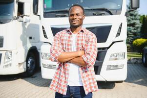 Front view. Young african truck driver is with his vehicle at daytime. photo