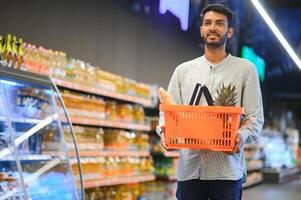 retrato de indio hombre adquisitivo en un tienda de comestibles almacenar. comprando tienda de comestibles para hogar en un supermercado foto