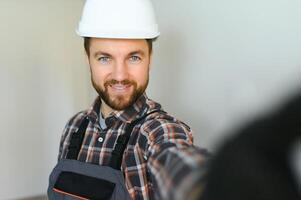 retrato de positivo, hermoso joven masculino constructor mientras trabajando a construcción sitio. foto