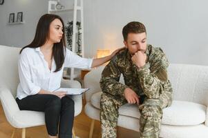 Sad male soldier on appointment with psychologist at office photo