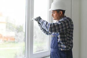 Indian service man installing window with screwdriver photo