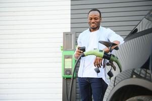 Man charging his electric car at charge station photo