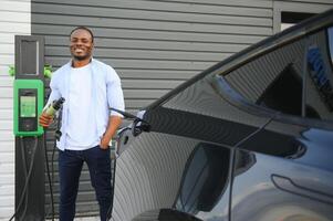 Man charging his electric car at charge station photo