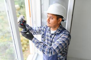 Indian service man installing window with screwdriver photo