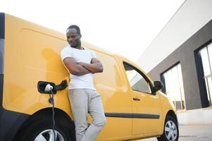 africano americano hombre cargando coche a vehículo cargando estación foto