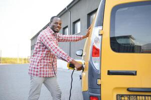 africano americano hombre cargando su eléctrico coche. foto