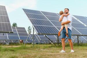 sonriente padre y su pequeño niño en antecedentes de solar paneles joven padre disfrutar gasto hora con su hijo. contento familia de dos en antecedentes de solar paneles foto