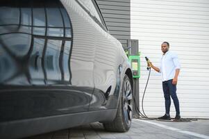 Man Plugging In Electric Car Outside Office In Car Park Charging photo