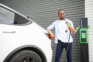 africano americano hombre cargando su eléctrico coche. foto