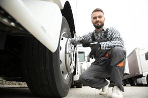 Working with damaged tire. Young truck driver is with his vehicle at daytime photo