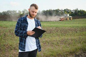 Agriculture. farmer working in a field in the background tractor plows ground in a field of wheat. farming agriculture concept. business farmer in the field photo