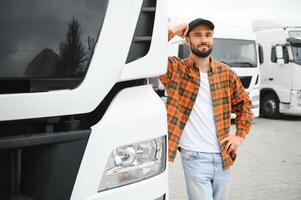 Portrait of young bearded trucker standing by his truck vehicle. Transportation service. Truck driver job photo