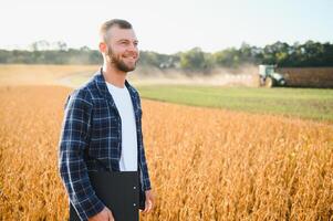 A young handsome farmer or agronomist examines the ripening of soybeans in the field before harvesting photo