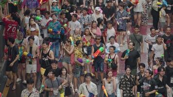 Bangkok, Thailand, April 13, 2024 - - thailändisch Neu Jahr oder Songkran Festival Tausende von Menschen versammeln beim Silom Straße Wasser Kampf Spritzen mit Wasser Gewehr video