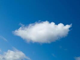 Single white fluffy cumulus cloud in the blue summer sky photo