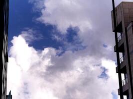 White fluffy clouds between apartment buildings, clouds background photo