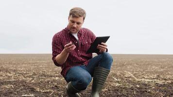 Farmer on a field with a tablet before planting agricultural cultures studies the condition of the soil video