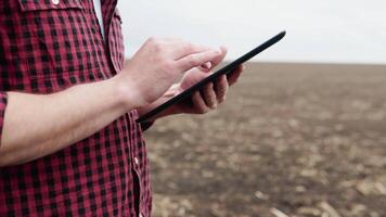 granjero en un campo con un tableta antes de plantando agrícola culturas video