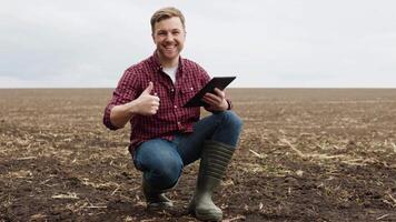 Portrait shot of attractive farmer in field, smiling cheerfully to camera and giving thumb up. Farmer with smile outdoors in summer video