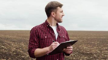 Farmer on a field with notebook before planting agricultural cultures video