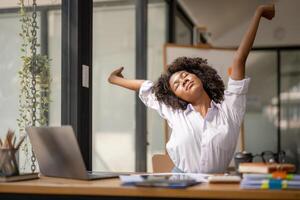 Black woman getting physically active from fatigue sitting at a desk. tired from work, Twisting due to pain, Office syndrome of office workers photo