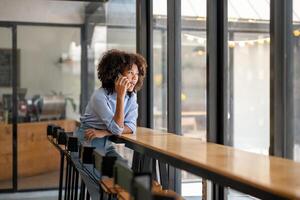 The black woman was talking on the phone and looked through the glass window outside. Talking on the phone in the cafe work area. photo