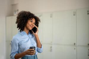 Black woman holding a cup of coffee and enjoying a phone call photo