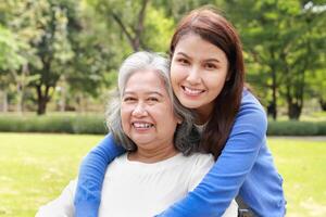 Elderly mother and daughter smiling happily in the park in the morning. Family concept. Health care for the elderly in retirement age. Nurses take care of the elderly. Close-up photo. photo