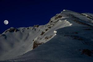 Snow-capped mountain illuminated by the moon photo