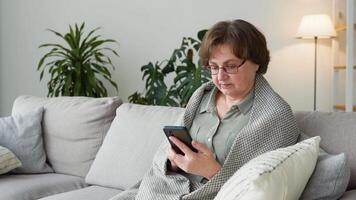 Older grandma enjoy using mobile app sit on sofa video