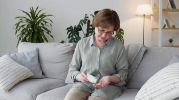 Senior adult woman holding painkiller pills on female hand pouring capsules from medical bottle video