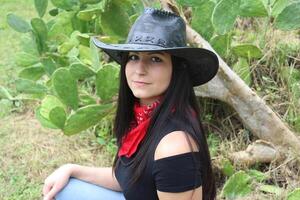 A Cowgirl in a Black Hat and a Red Bandana by a Cactus. photo