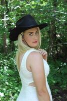 A Woman in a White Dress and a Black Cowboy Hat. photo