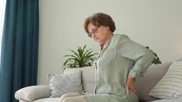 Mature woman sits on the bed and touches back, radiculitis and pain video