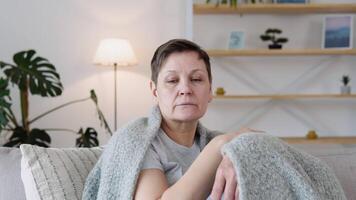 triste più vecchio adulto donna guardare a telecamera sedersi su divano solo a casa. video