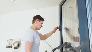 Senior mulher limpeza janela às casa com uma vácuo limpador. profissional limpeza mulher durante trabalhos video