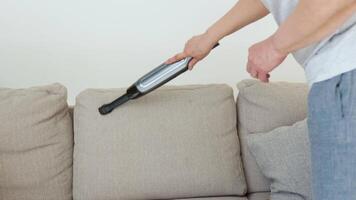 Senior woman vacuuming sofa manual vacuum cleaner. Professional cleaning woman during work video