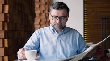 Senior man spending time in cafe, reading newspaper and having coffee cup video