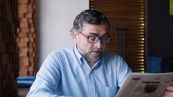 Mature male reads the press while sitting in a cafe. The pensioner is resting video