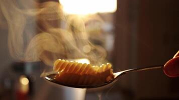 klar att äta varm, al dente pasta fusilli i en sked, bakgrundsbelysning, ånga stiger ovan. italiensk kök. hemmafru matlagning traditionell recept för maträtt förberedelse i en kök. video