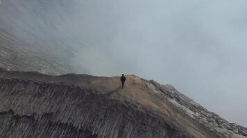 Man stands cliff volcano drone video