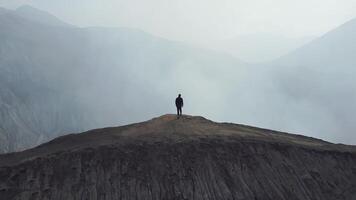 Man stands cliff volcano crater video