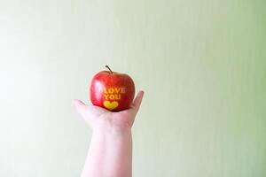 Fresco rojo manzana en mano con palabras yo amor usted y corazón foto