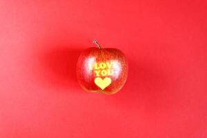 Ripe apple with words I LOVE YOU on red background. photo