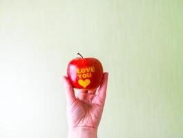 Fresh red apple in hand with words I love you and heart photo
